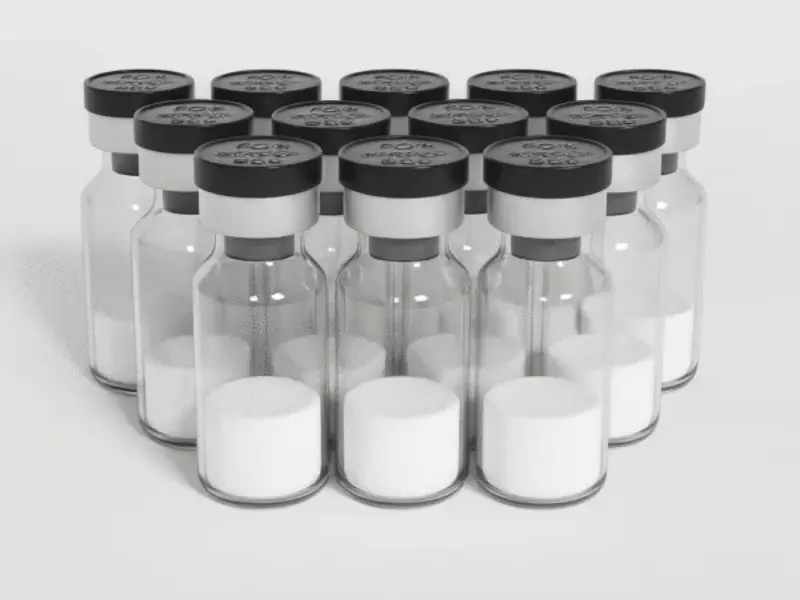 Multiple clear glass research vials with silver caps and Human Growth Hormone powder inside, arranged in rows.